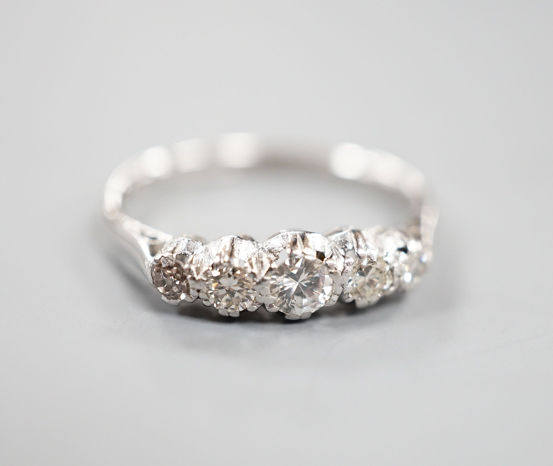 An 18ct & plat, graduated five stone diamond half hoop ring, size L/M, gross weight 2 grams.